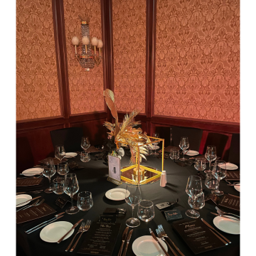 uxury table centrepiece with black florals, gold palm leaves and elegant event décor for gala events.