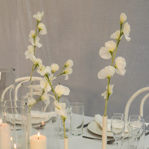 candles and floral vases with sweet pea stems