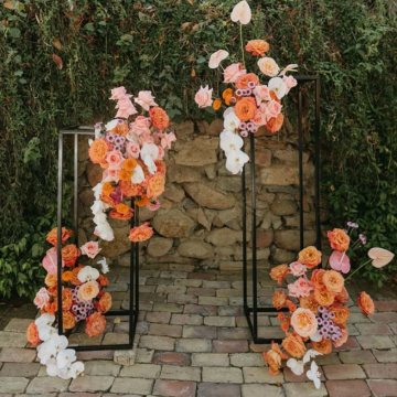 black floral stand with sunset orange flowers