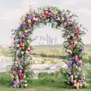 wedding arch with purple accented florals 