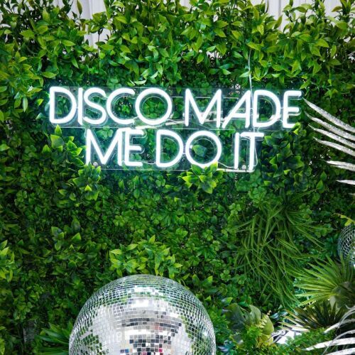 disco made me do it neon sign on greenery wall