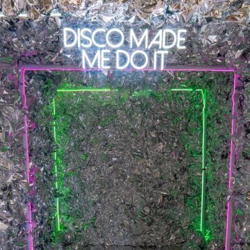 disco made me do it neon sign on crinkle wall entranceway