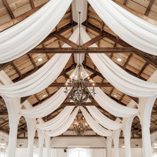 white chiffon drape over beams in barn wedding