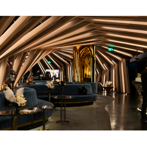 Luxury lounge styling featuring white artificial florals, gold foliage and ostrich feathers displayed on black side tables in a modern event venue.