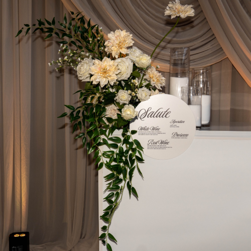 Ivory Garden Floral Feature with ivory artificial roses, cascading greenery and faux florals styled on a wedding bar display with elegant draping backdrop.
