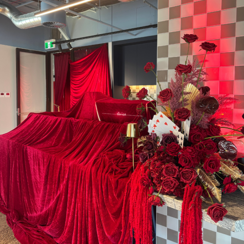 Ruby Royale Floral Feature with deep red artificial roses, gold foliage and faux florals styled on a luxury casino-inspired wedding bar display.