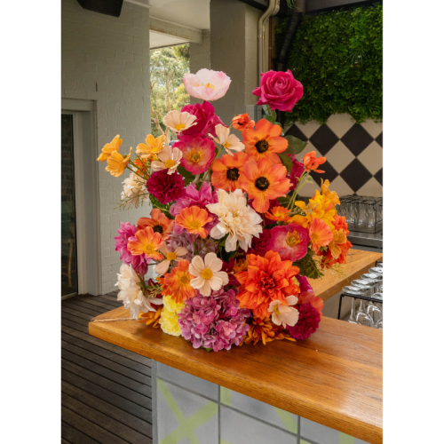 Sunset Fiesta Floral Feature with vibrant orange and pink artificial flowers styled on a cocktail bar for colourful wedding and event dÃ©cor.